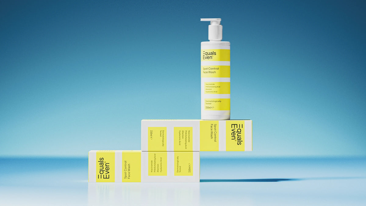 A white pump bottle labeled Spot Control Face Wash—a gentle cleanser that removes impurities—stands on three matching yellow-and-white boxes, all arranged creatively against a blue gradient background.